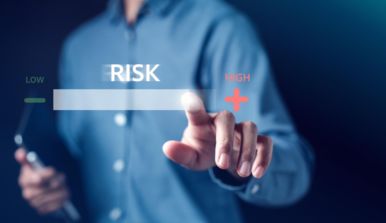 Businessperson interacting with a digital risk level gauge, indicating varying levels of business risk from low to high—symbolizing risk assessment and decision-making in cybersecurity.